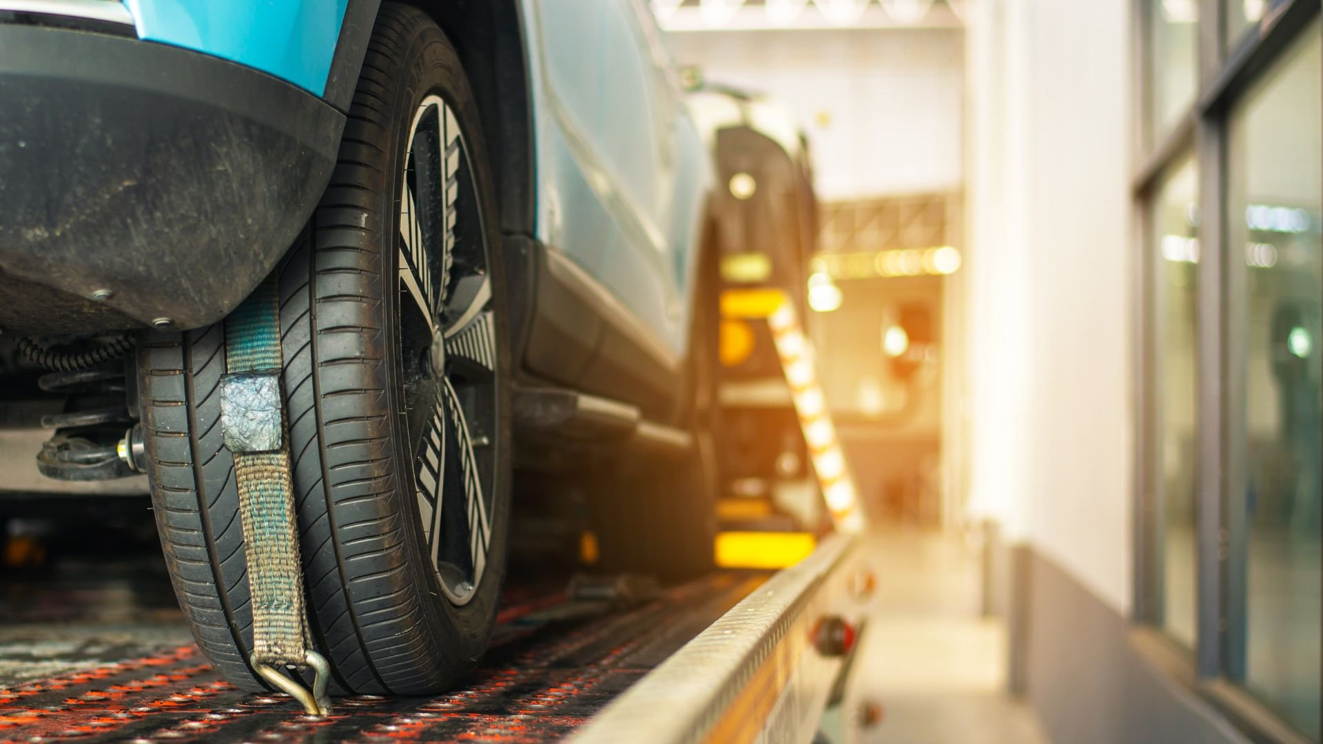 Car tire secured on platform with tie-down strap at automotive service center