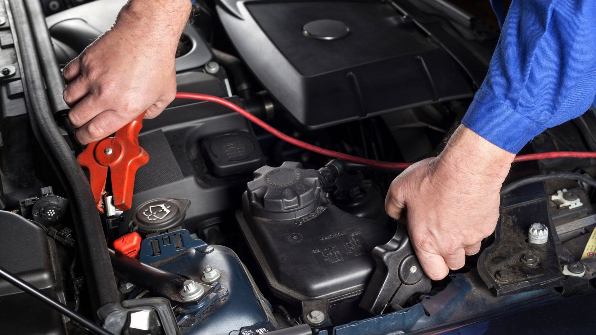 Mechanic using jumper cables to charge a car battery