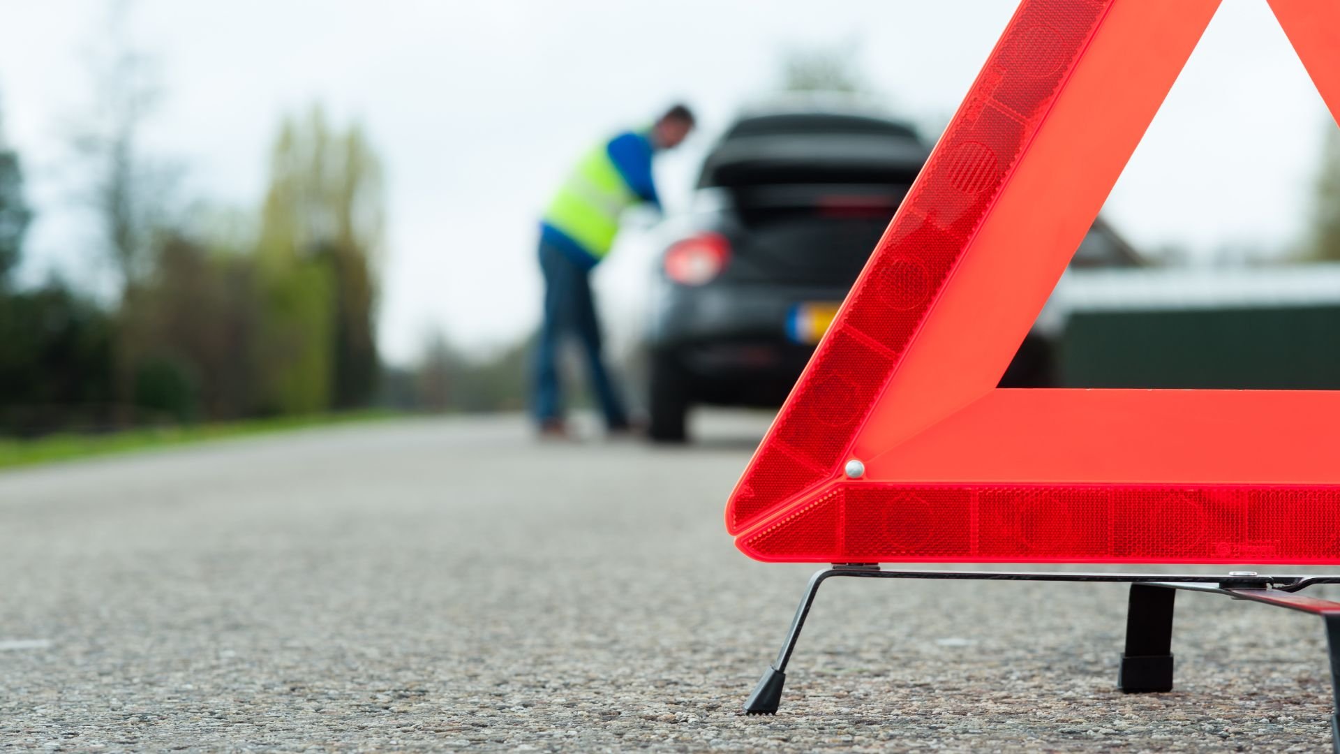 Red warning triangle with broken down car on roadside