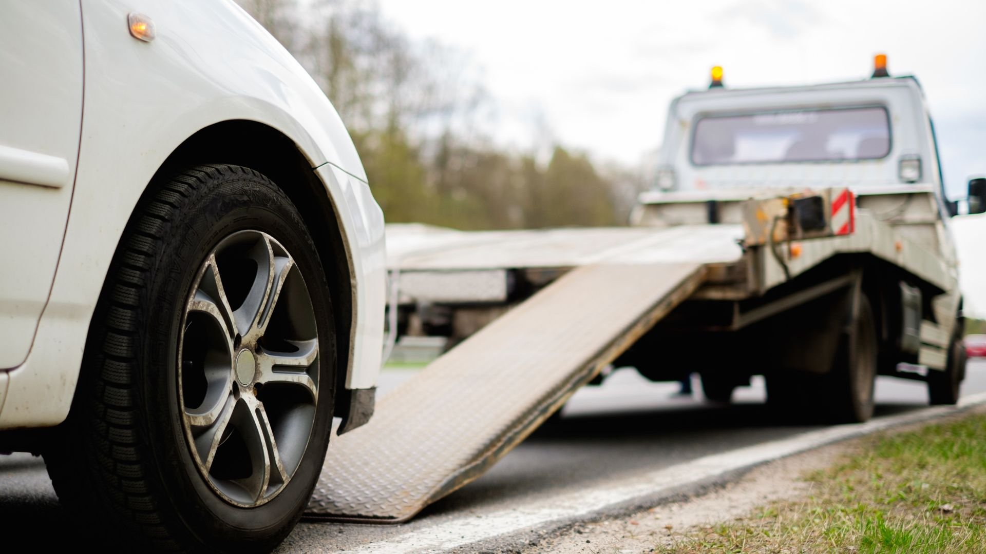 White car being loaded onto a tow truck on a roadside