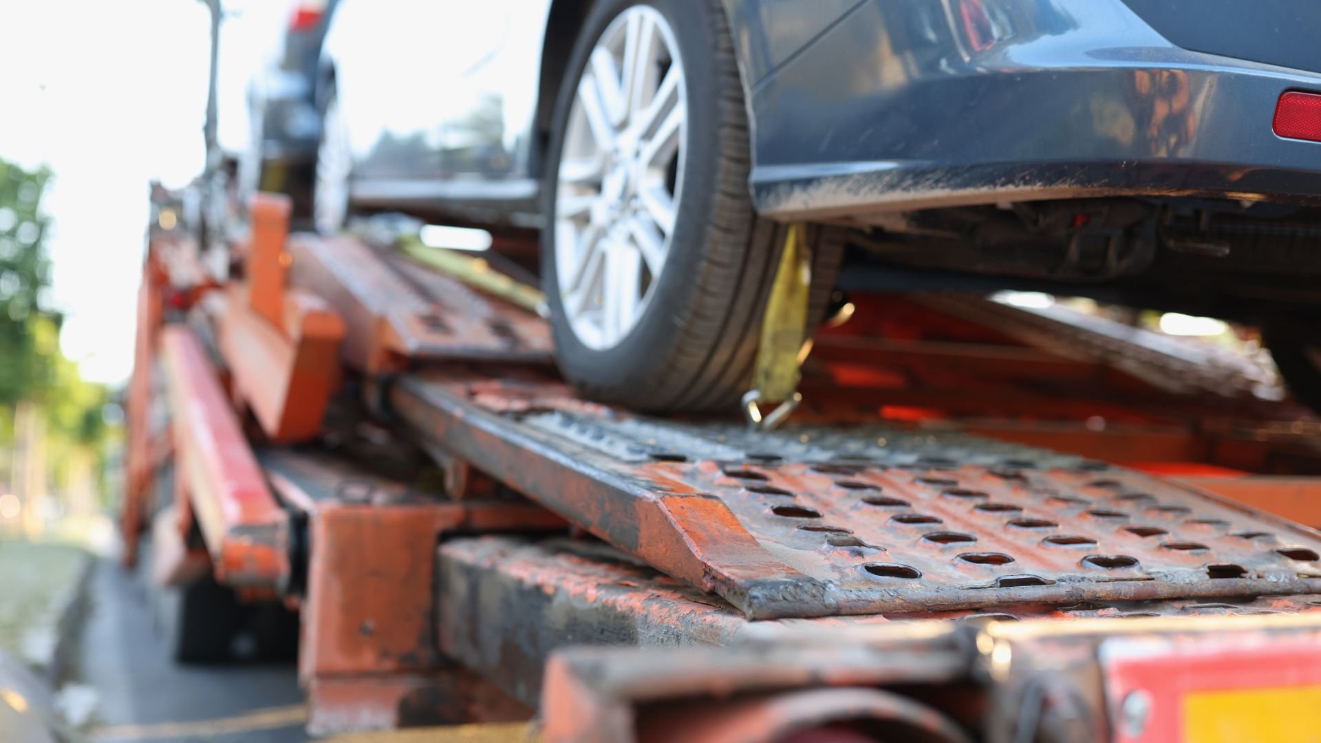 Blue car loaded on rusty tow truck transport platform